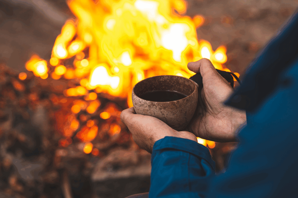 Mains tenant une tasse en bois près d'un feu de camp lors d'une retraite hivernale de Minds and Mountains.